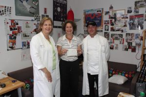Foto der Spendenübergabe im RUMMS-Studio mit RUMMS-Redakteurin Stephanie und zwei Vertretern des UMM-Küchenteams